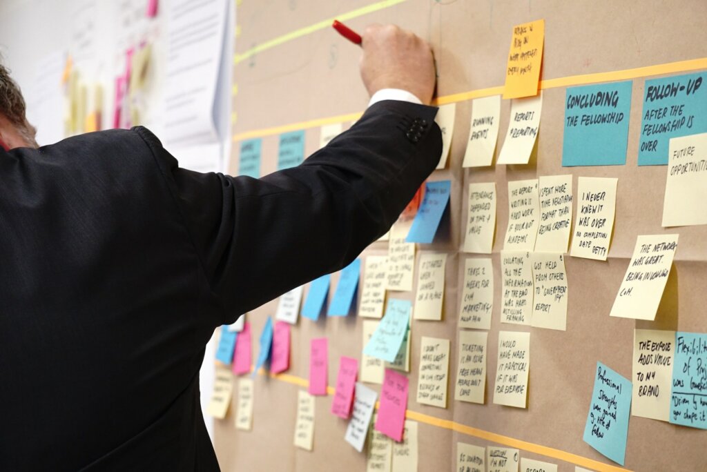 Man writing on a board with sticky notes attached