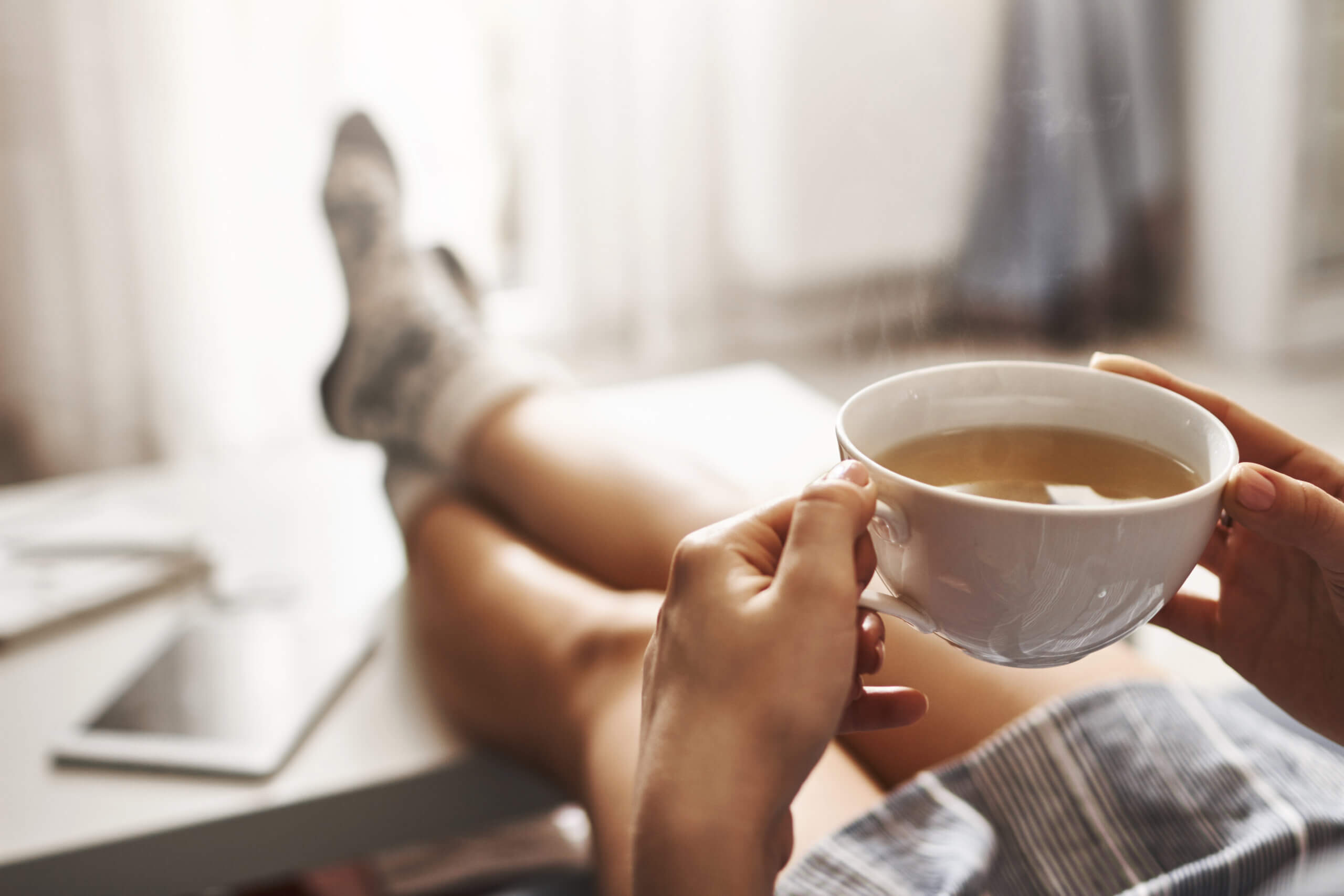 Person relaxing with a cup of tea and their feet up